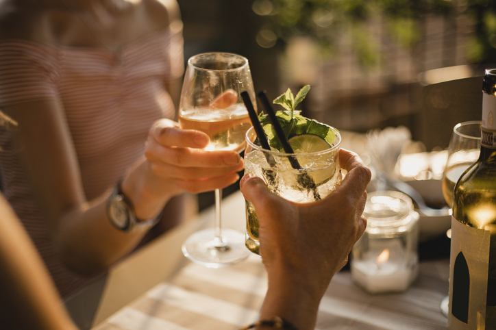 Two hands cheersing with glasses of wine at a dinner table.